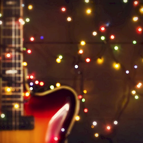 A close-up of a guitar with colorful string lights in the background creates a festive and artistic atmosphere.