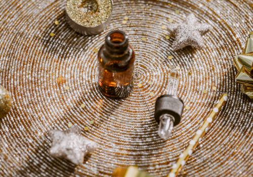 An amber dropper bottle, a small bulb syringe, and tiny ornaments on a glittery, spiraled surface with stars and festive decor.