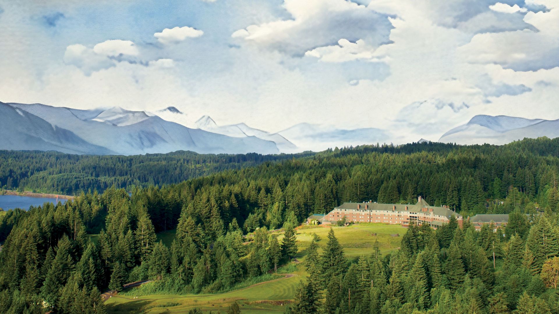 A large building surrounded by dense forest, with mountains and a lake in the background under a partly cloudy sky.