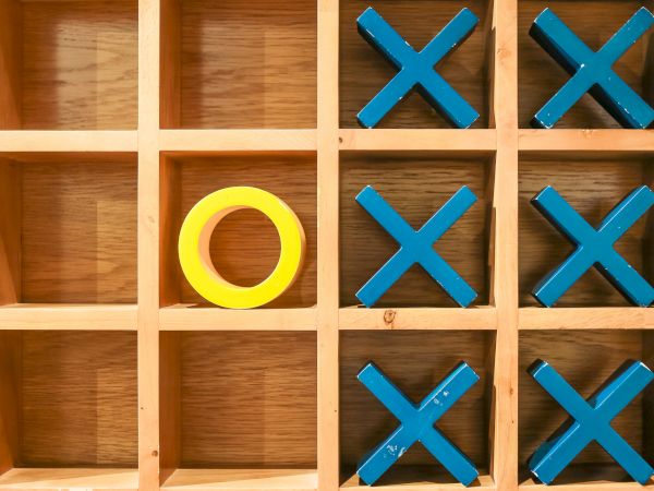 A tic-tac-toe board with yellow O and blue Xs; the O is in the middle-left square.