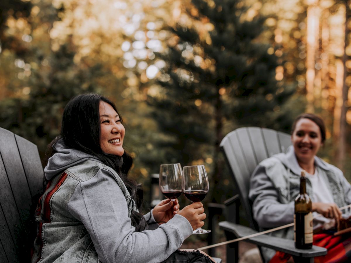 Two friends enjoy an outdoor meal, clinking wine glasses in the golden evening light.