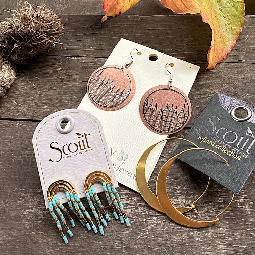Beaded earrings on display: turquoise tassel beads, round bronze designs, and gold hoop jewelry on cards.