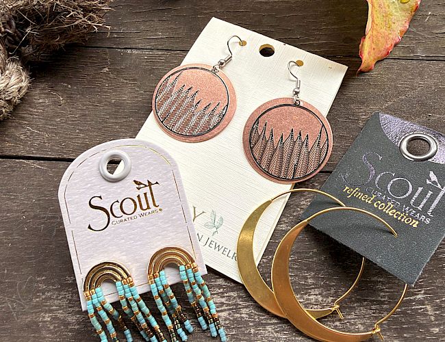 Beaded earrings on display: turquoise tassel beads, round bronze designs, and gold hoop jewelry on cards.