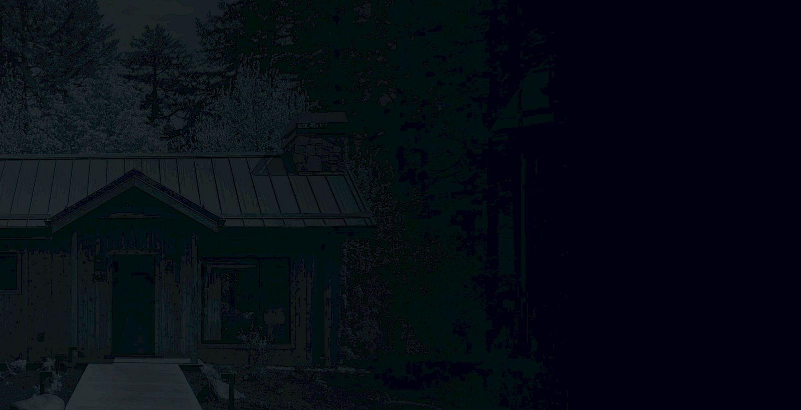 The image shows a wooden house with a metal roof and stone chimney, surrounded by trees and greenery, creating a serene, rustic atmosphere.