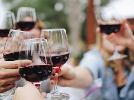 People clinking glasses of red wine in a celebratory toast, creating a festive and joyful atmosphere.