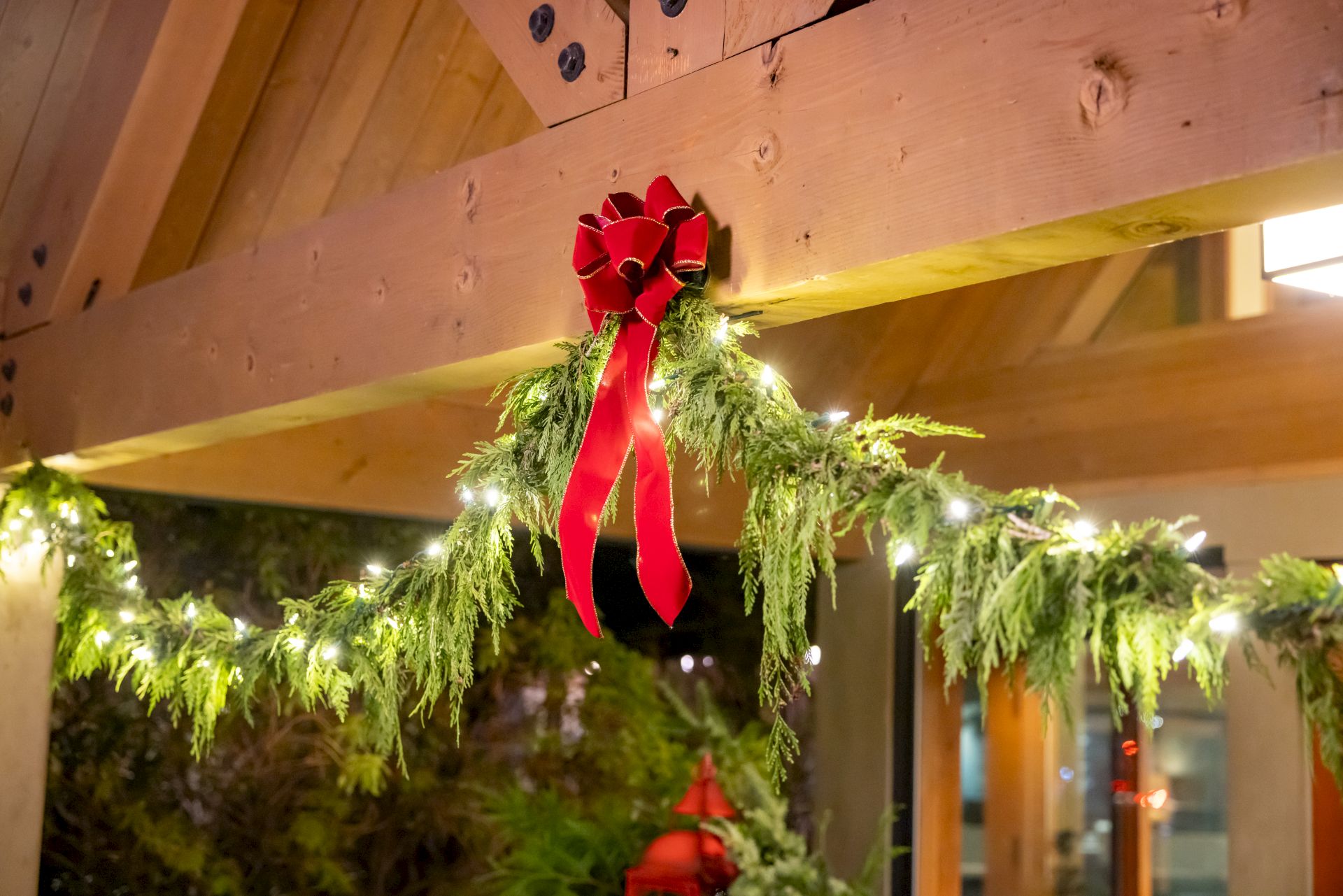 A festive garland with lights and a red bow decorates a wooden beam, creating a cozy holiday atmosphere.