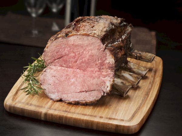 A juicy roast beef slab on a cutting board with a herb garnish, tender pink center and browned crust, sliced for serving.